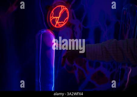 hand touches a glowing plasma ball in a dark laboratory, creating a mesmerizing display of electricity, suggesting advancements in energy or scientifi Stock Photo