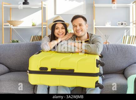 Young tourist couple at home, happy planning bright summer trip holiday, beach, packed luggage  Stock Photo