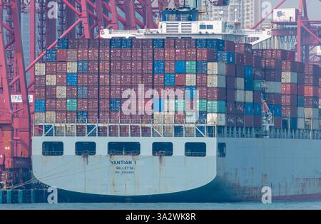 Hong Kong. China- 02.18.2025. Close up of a container cargo ship laden with cargo, docked by the quay cranes in the Port of Hong Kong. Stock Photo