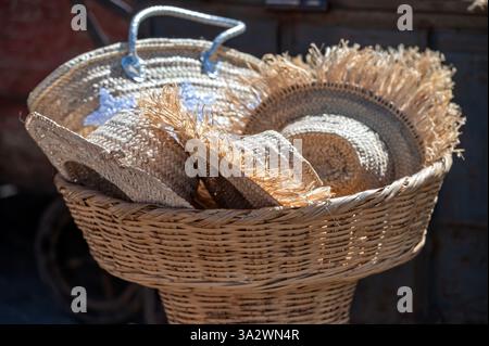 Colorful straw hats are displayed in woven baskets at a bustling Marrakech market. Stock Photo