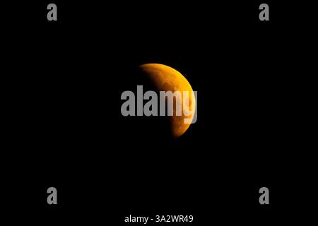 A lunar eclipse is visible above Surrey Quays in London as the full moon passes into Earth's shadow. Unlike in other parts of the world, except for some extreme western areas of the UK, the eclipse will be almost entirely partial. A lunar eclipse occurs when the Earth, sun, and moon are almost exactly in line and the moon is on the opposite side of the Earth from the sun. Picture date: Friday March 14, 2025. Stock Photo