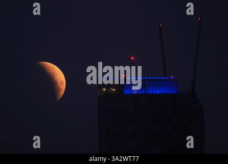 A lunar eclipse is visible above Canary Wharf in London as the full ...