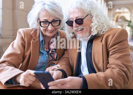 Happy senior couple using smartphone together, smiling and enjoying technology. Stock Photo