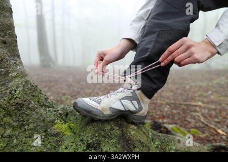 Close up portrait of a trekker tying shoelaces of boots in nature Stock Photo