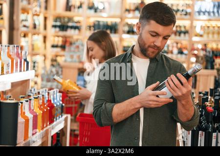 Man and woman are choosing wine in the shop. Stock Photo