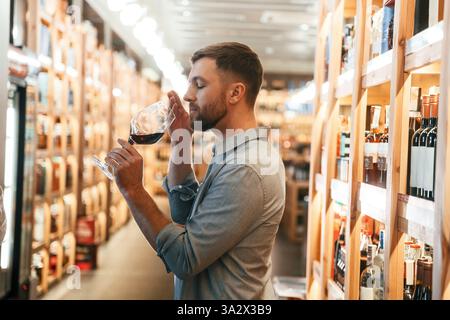 Drink tasting. Man is choosing wine in the store. Stock Photo