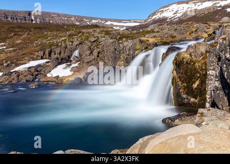 Hrisvadsfoss waterfall downstream of the big Dynjandi waterfall in Westfjords, Iceland, long exposure view with rainbow and volcanic stones. Stock Photo