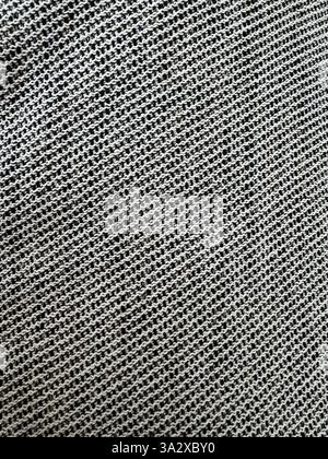 Textured gray fabric showing intricate woven patterns under natural light conditions Stock Photo