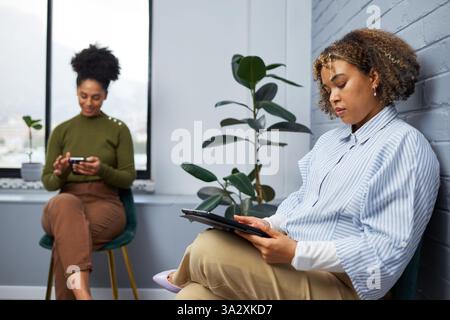 Professionals Sitting in a Modern Office Space and Using Digital Devices Stock Photo