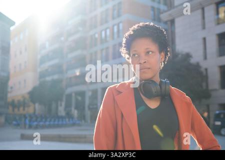 Woman with headphones stands confidently in the city Stock Photo