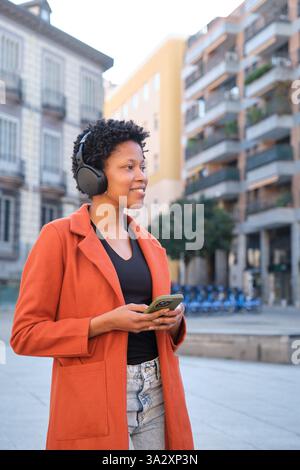 Young woman enjoying music while exploring the city Stock Photo