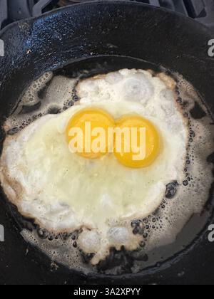 Frying double yoked egg in iron skillet in butter. Stock Photo