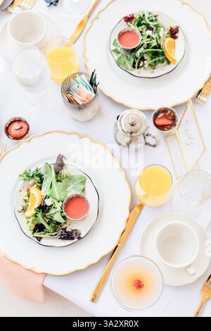 Elegant table setting with salad, orange juice, and silverware. Stock Photo