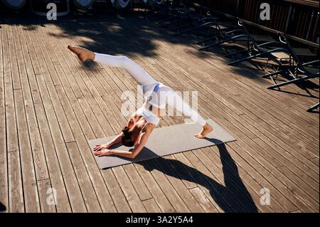 Stretching the legs. Young woman in fitness clothes is outdoors. Stock Photo
