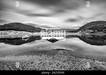 house reflected in the Villajoyosa reservoir with moving clouds Stock Photo