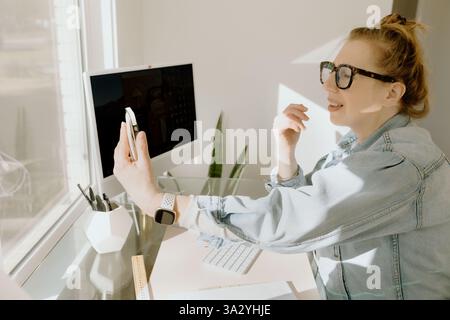 A business woman smiles during a video call in her bright home office Stock Photo