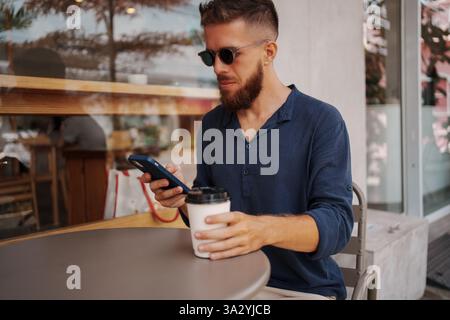 Stylish Man Enjoying Coffee While Using Phone at Caf Stock Photo