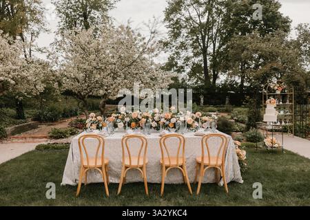 Elegant outdoor wedding reception table with floral decor in a garden Stock Photo
