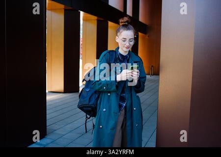 Student girl or teenager in eyeglasses using her smartphone Stock Photo