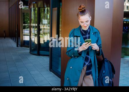 Student ginger girl using a smartphone Stock Photo