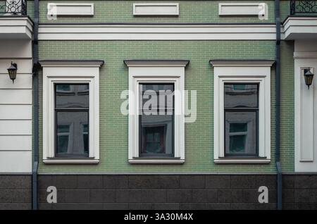 Facade of an old building. Building with green tiled facade and white window surrounds. Green house in old town. Stock Photo