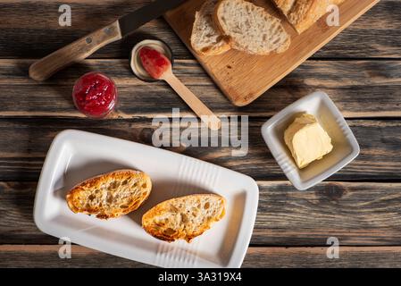 Ingredients to make toast with country bread slices, butter, and raspberry jam. Stock Photo