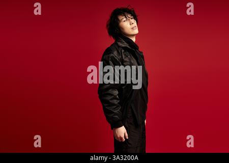 Stylish young man in black strikes a confident pose in studio. Stock Photo