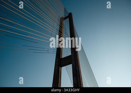 Suspension bridge tower at sunset. Looking up at the concrete pylons of cable-stayed bridge. Stock Photo