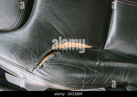 Torn, ripped, damaged car leather seat upholstery. Top down view, close up, no people. Stock Photo