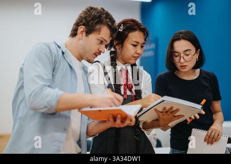 Three students collaborating on a group project in a classroom Stock Photo