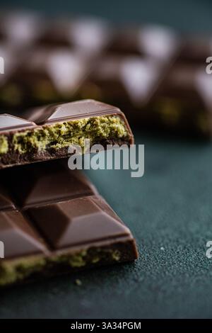 Close-up view of a handmade milk chocolate bar infused with vibrant green pistachio nut paste, often referred to as Dubai chocolate. The image showcas Stock Photo