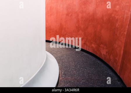 An eye-catching minimalist architectural detail featuring a smooth white column juxtaposed with a vibrant red textured wall, highlighting the beauty i Stock Photo