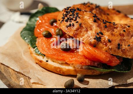 Close-up of a tasty bagel topped with smoked salmon, capers, and fresh greens. Perfect for breakfast or brunch, the bagel features a golden, sesame se Stock Photo