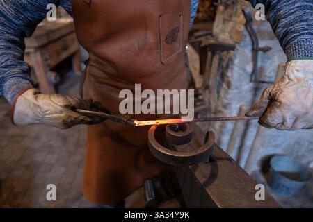 An elderly blacksmith in Salzburg, Austria, keeps centuries-old blacksmithing traditions alive in his workshop. The image captures the essence of his Stock Photo