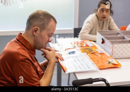Individuals engage in meaningful activities at a day center for intellectual disabilities. The setting fosters learning, creativity, and social intera Stock Photo