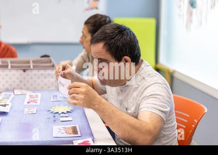 A person with a mental disability engages in a structured activity at a day center, illustrating support, learning, and care in a nurturing environmen Stock Photo