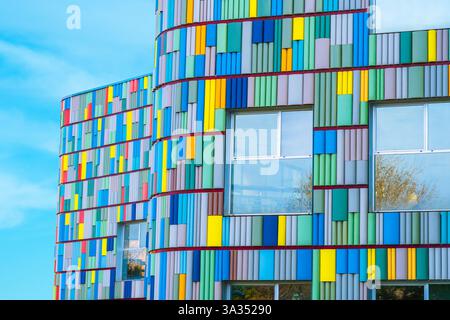 A stunning view of a modern building's curved facade adorned with multicolored panels. Bright blues, yellows, reds, and greens create a visually capti Stock Photo