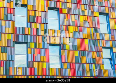 A detailed view of a building facade covered in a multitude of brightly colored panels arranged in a geometric pattern, highlighting modern architectu Stock Photo