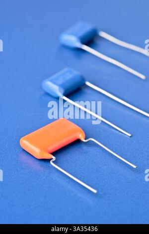 Close-up of orange and blue capacitors laid on a vibrant blue background. This image showcases electronic components used in various circuits. Stock Photo