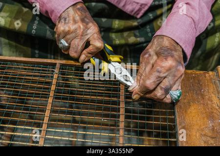 Close up of balinese hands using pliers to craft with wire. The image captures the essence of craftsmanship and handiwork, focusing on traditional ski Stock Photo