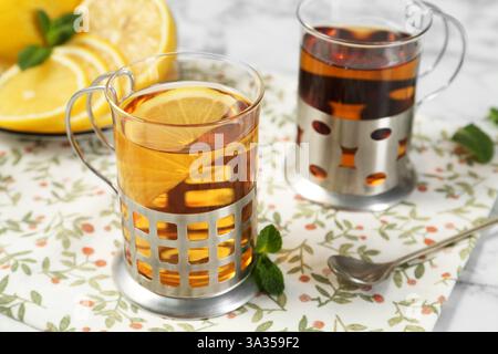 Glasses of tea in metal holders served on white table, closeup Stock Photo