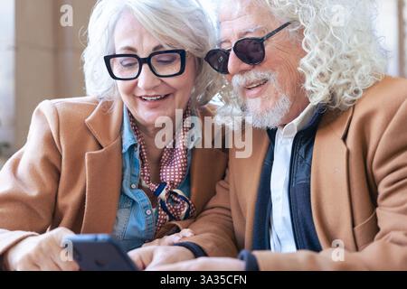 Happy senior couple using smartphone together, smiling and enjoying technology. Stock Photo