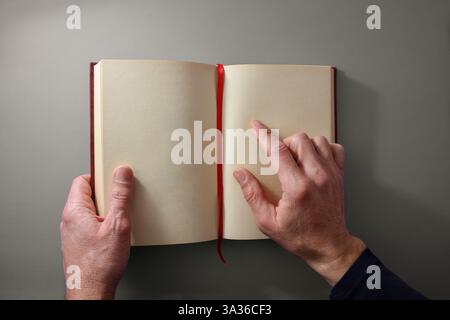 Concept of a person reading a book with one hand holding the book and the other hand pointing at a page of a book with blank sheets and a red registra Stock Photo