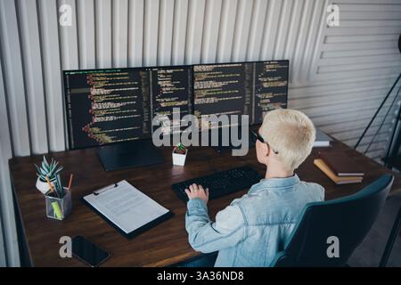 Programmer Working on Dual Screens in Modern Workspace with Casual Style Stock Photo