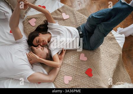 A lot of heart shaped paper decorations, top view. Young couple are together at home. Stock Photo