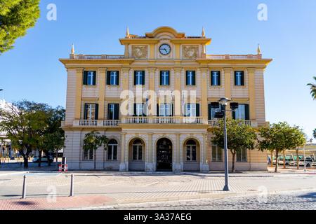 The architecture of the city hall building stands tall and symmetrical against a cloudless blue sky in San Fernando, Spain. Stock Photo