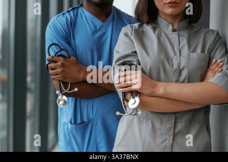 Man and woman doctors are standing together indoors with stethoscope. Stock Photo