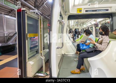 doors, open door, platform, the interior of a RapidKL Scomi SUTRA train in Kuala Lumpur, Malaysia, female commuters on board sitting Stock Photo