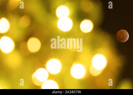 Santiago, Santiago, Chile. 14th Mar, 2025. A total lunar eclipse is visible at its peak stage through string lights on a street in Santiago, Chile. (Credit Image: © Matias Basualdo/ZUMA Press Wire) EDITORIAL USAGE ONLY! Not for Commercial USAGE! Stock Photo