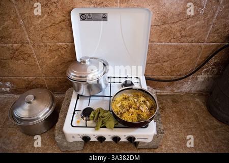 Jul 26, 2014 - Hamdaniyah, Iraq - Lunch is seen cooking on a gas cooker used by 17 members of an extended family of Iraqi Christian refugees from Mosul in their partially built house in Hamdaniyah, Iraq. The family left Mosul on Friday the 18th of July when Islamic State fighters issued an ultimatum to the city's Christian community. When the family left they were forced to pay a tax for their car, and one son (19) was threatened at knifepoint to ensure they handed over all of their possessions including family photographs. Having taken over Mosul Iraq's second largest city in June 2014, rebel Stock Photo